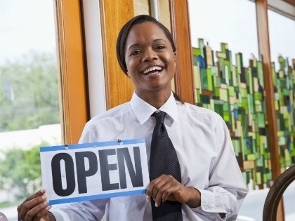 Female business owner holding a sign that says "open"